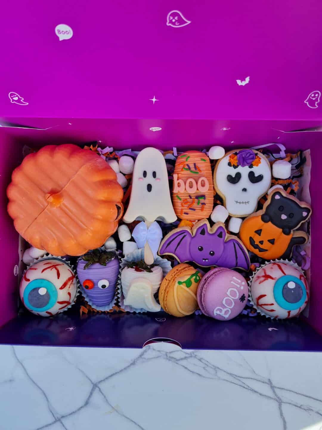 Bandeja con cupcakes decorados con temática de Halloween, en colores naranja, morado y blanco.