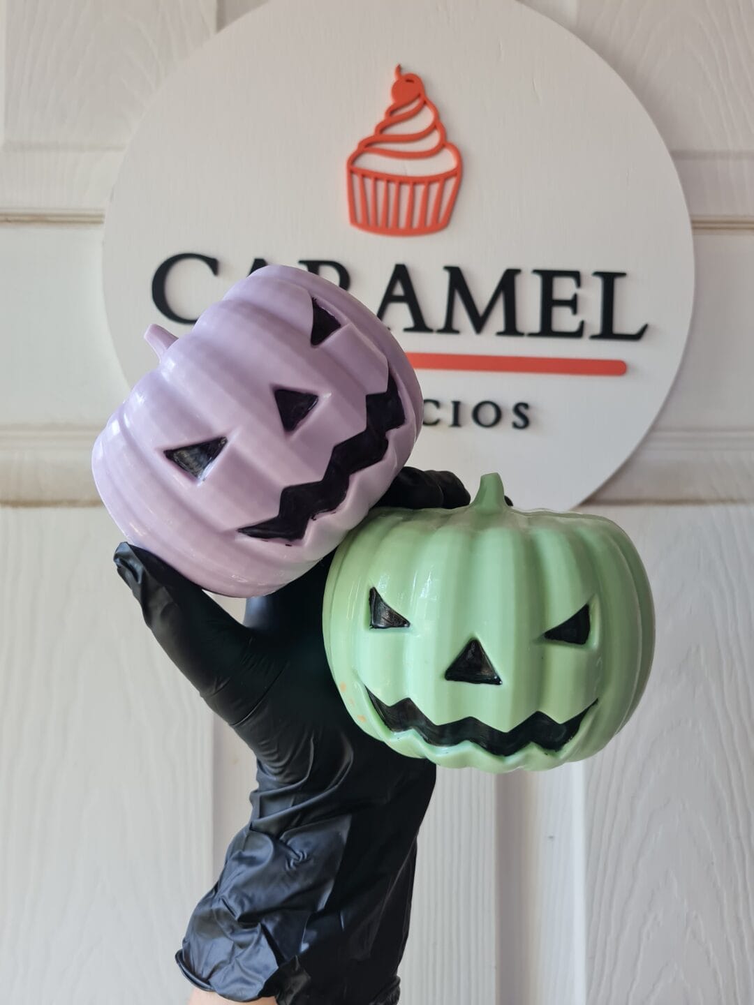 Calabazas de Halloween decorativas en tonos morado y verde con caras sonrientes y aterradoras.
