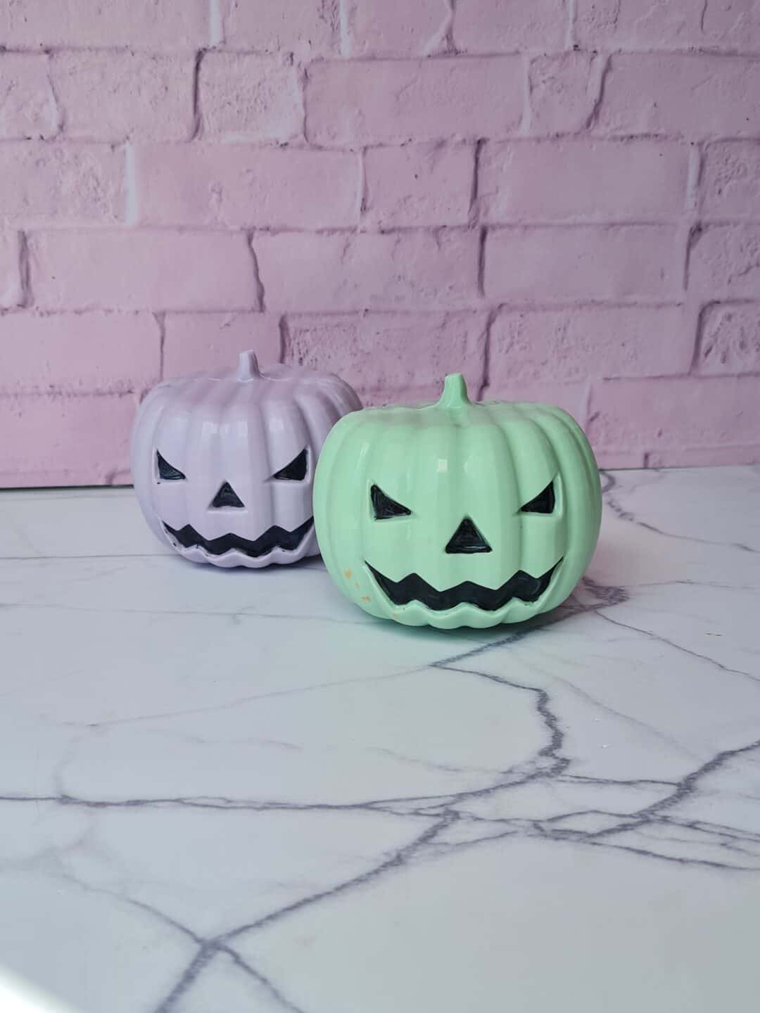 Calabazas decorativas de cerámica con caras de Halloween en tonos blanco y verde.