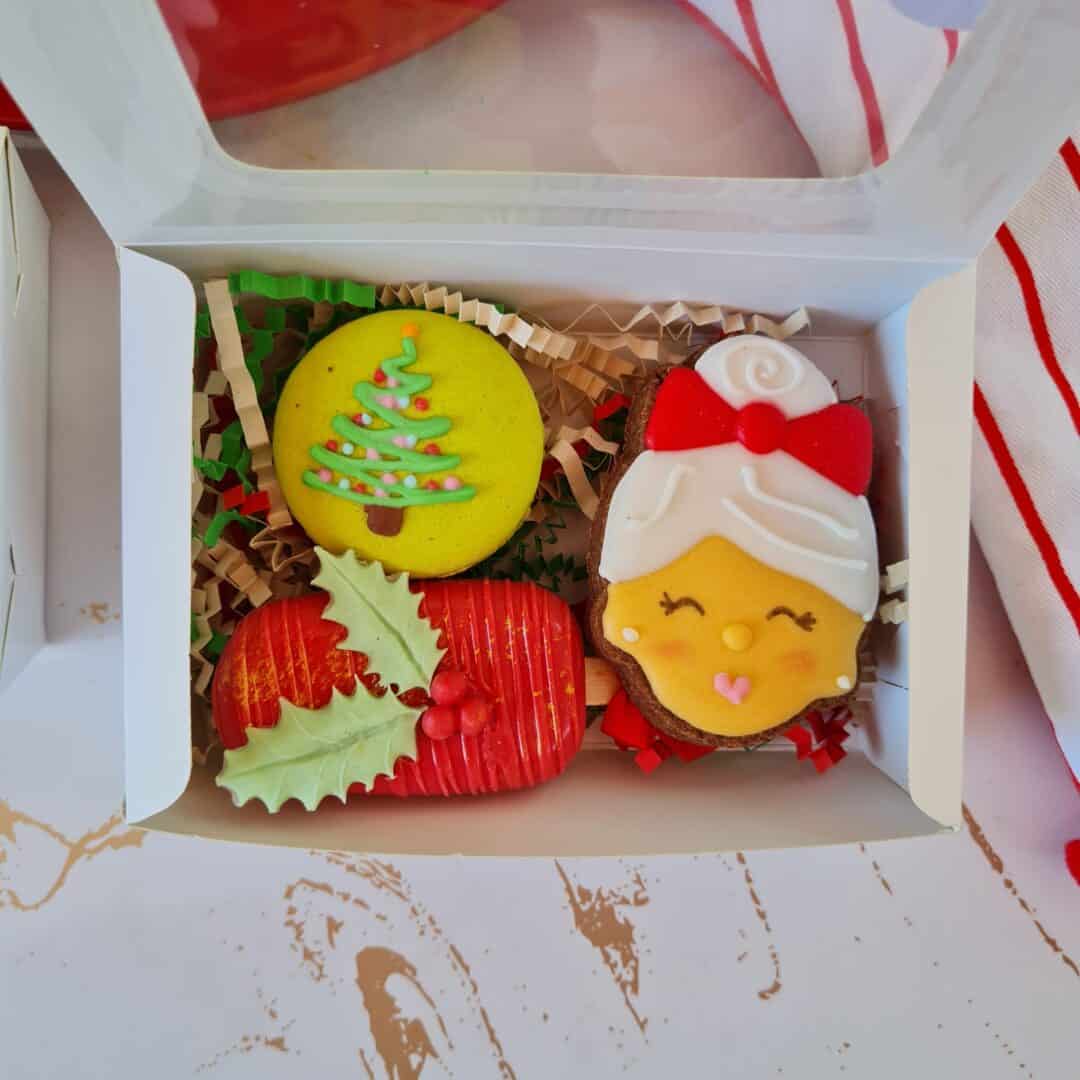 Galletas navideñas decoradas en caja, con motivos festivos y colores tradicionales.