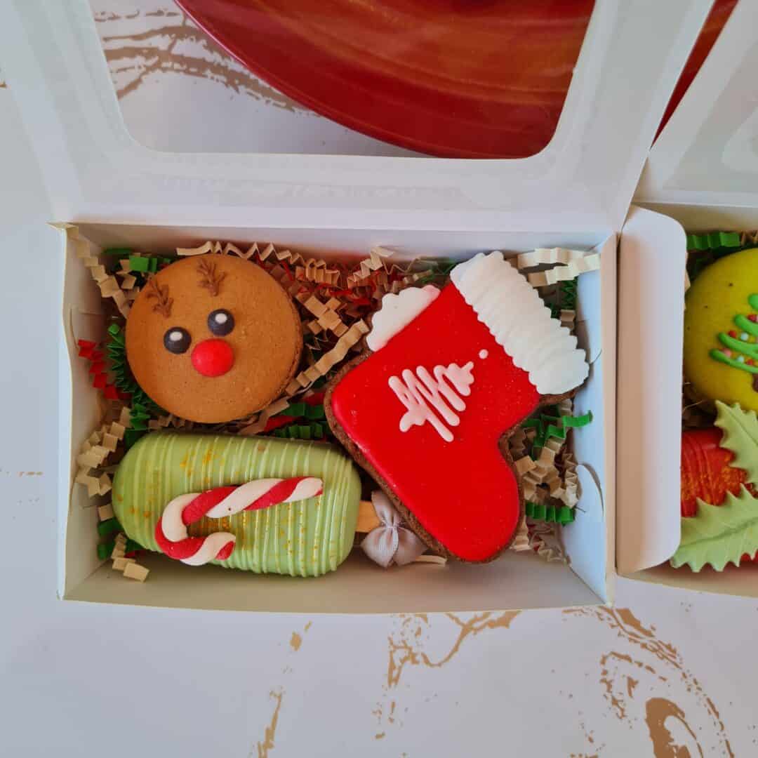 Caja con galletas navideñas decoradas, incluyendo calcetín, reno y bastón de caramelo.
