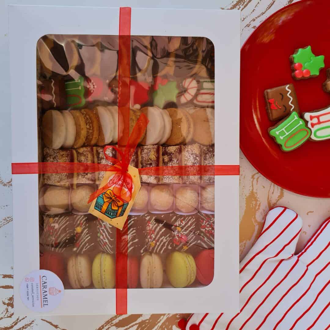 Macarons surtidos en caja con decoración navideña y regalos.