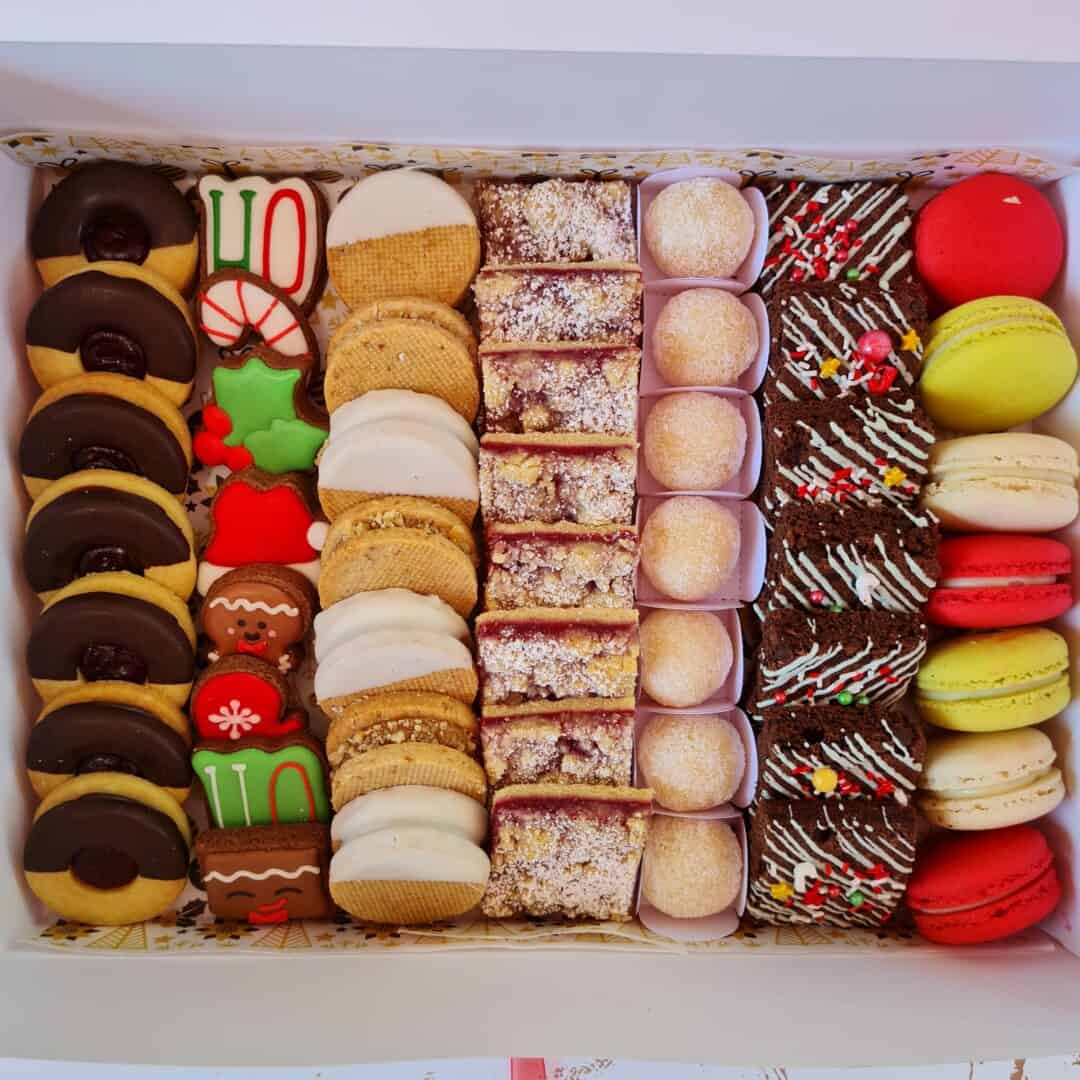 Pastelería francesa y macarons en caja con decoraciones navideñas y dulces variados.