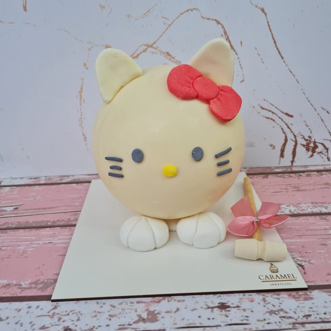 Gato de fondant con lazo rojo y detalles en color negro y amarillo, decorado con una piñata en el pa.