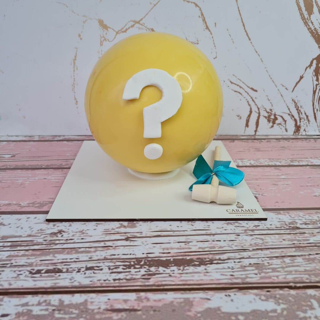 Bola de piñata amarilla con signo de interrogación blanca en el centro, acompañada de un pequeño reg.