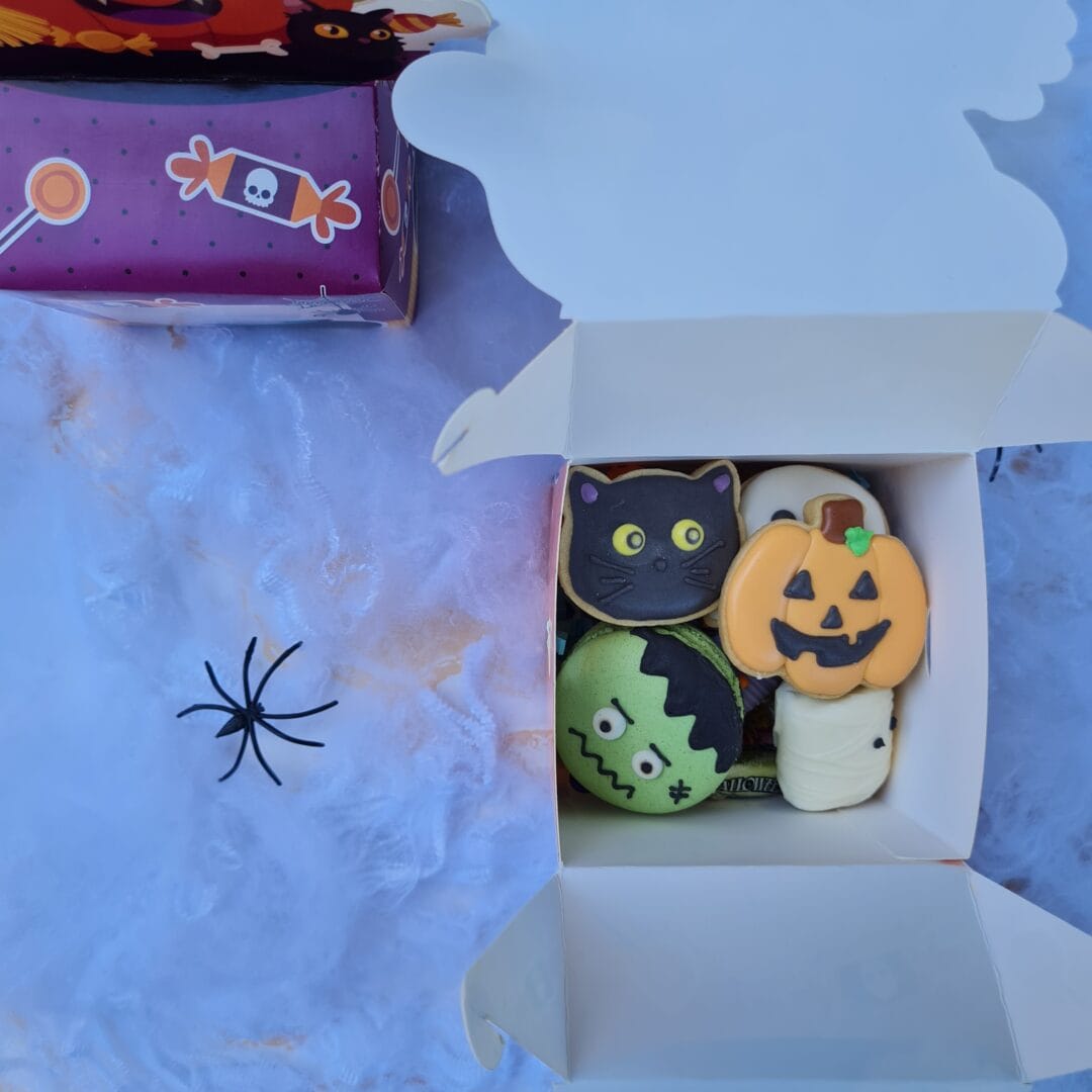 Calaveritas de galleta decoradas con motivos de Halloween en caja de cartón.
