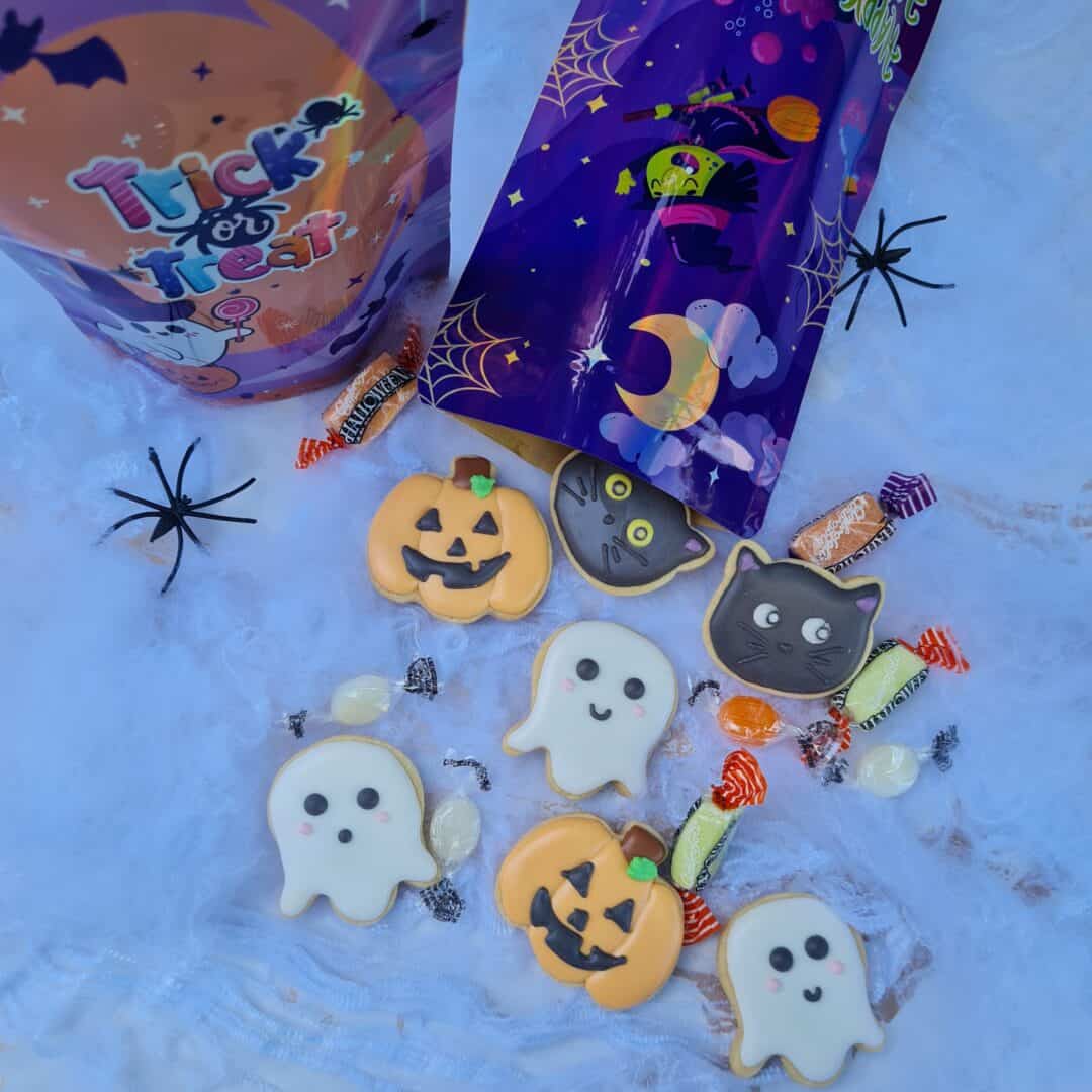 Dulces de Halloween con calabazas, fantasmas y gatos en envoltorios coloridos.
