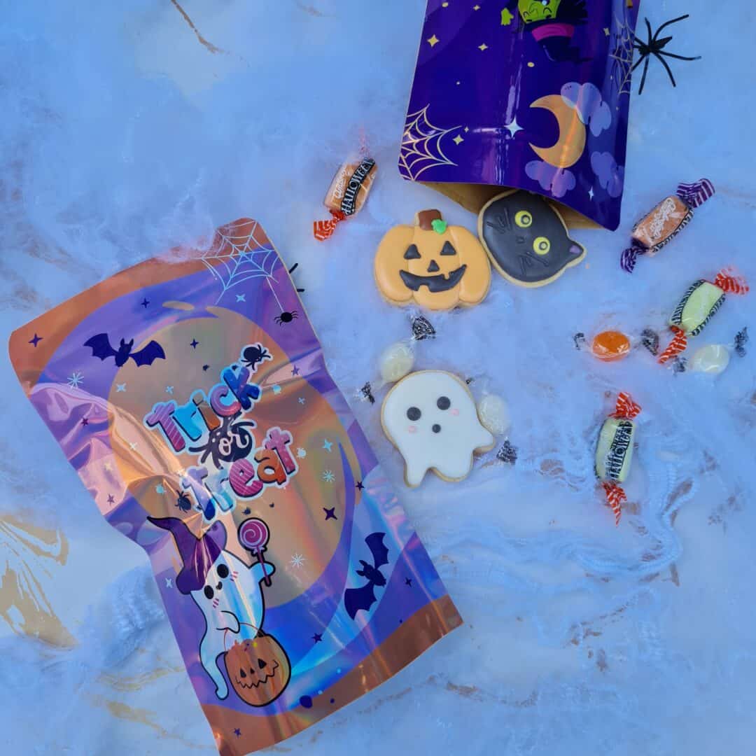 Dulces de Halloween con caramelos y galletas decoradas en un fondo de hielo.