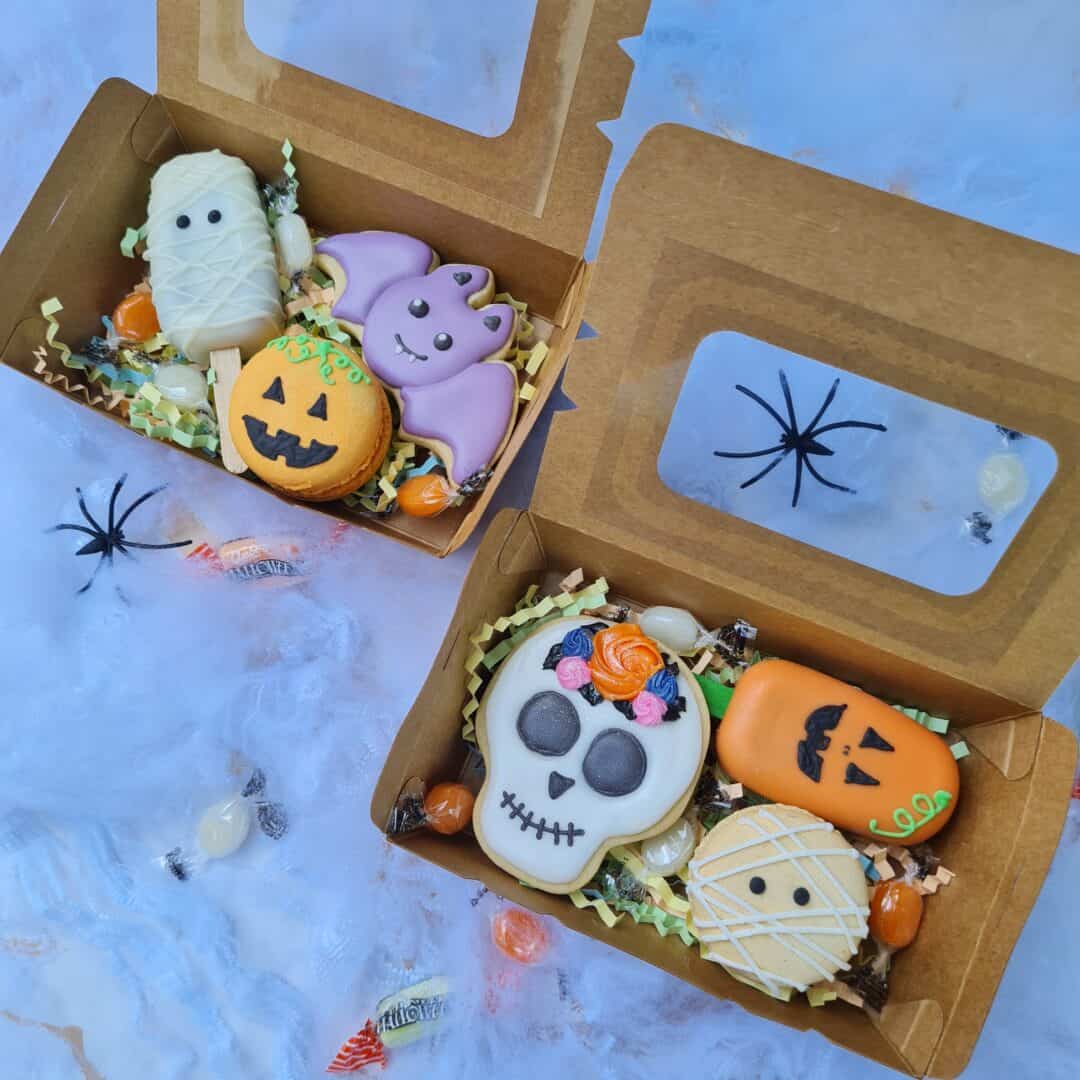 Caja con galletas decoradas de Halloween y caramelos en caja de cartón.