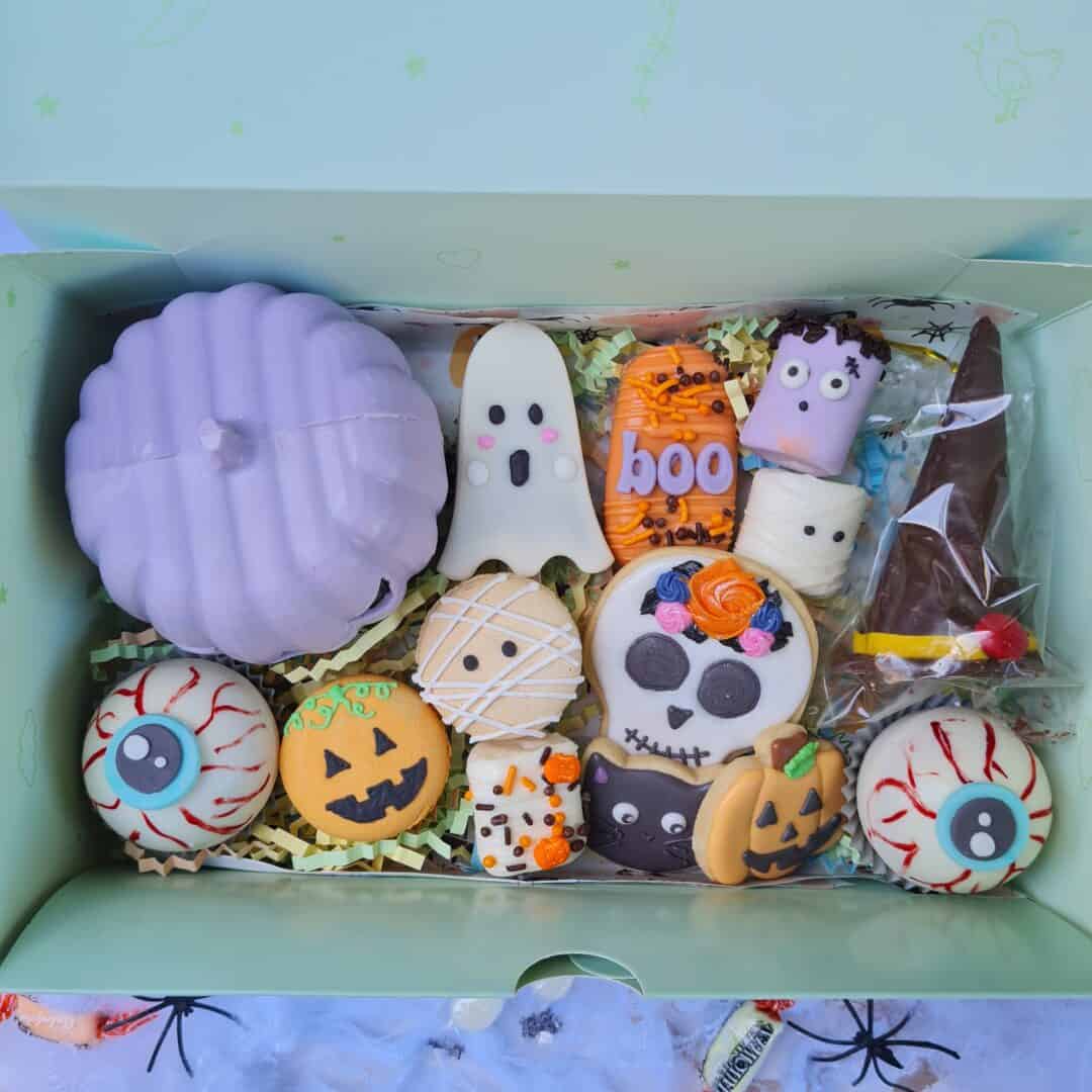 Galletas decoradas con temática de Halloween en caja de pastelitos.