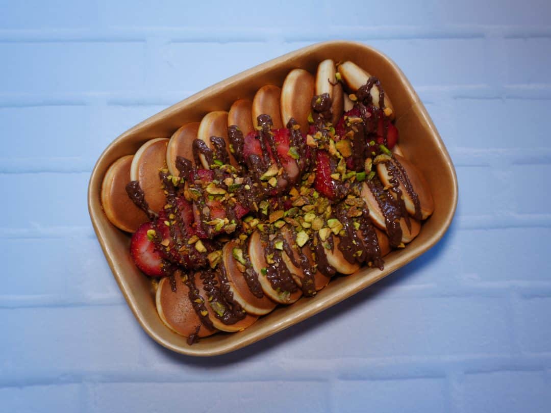 Galletas de chocolate con frutas y pistachos en bandeja de cerámica.