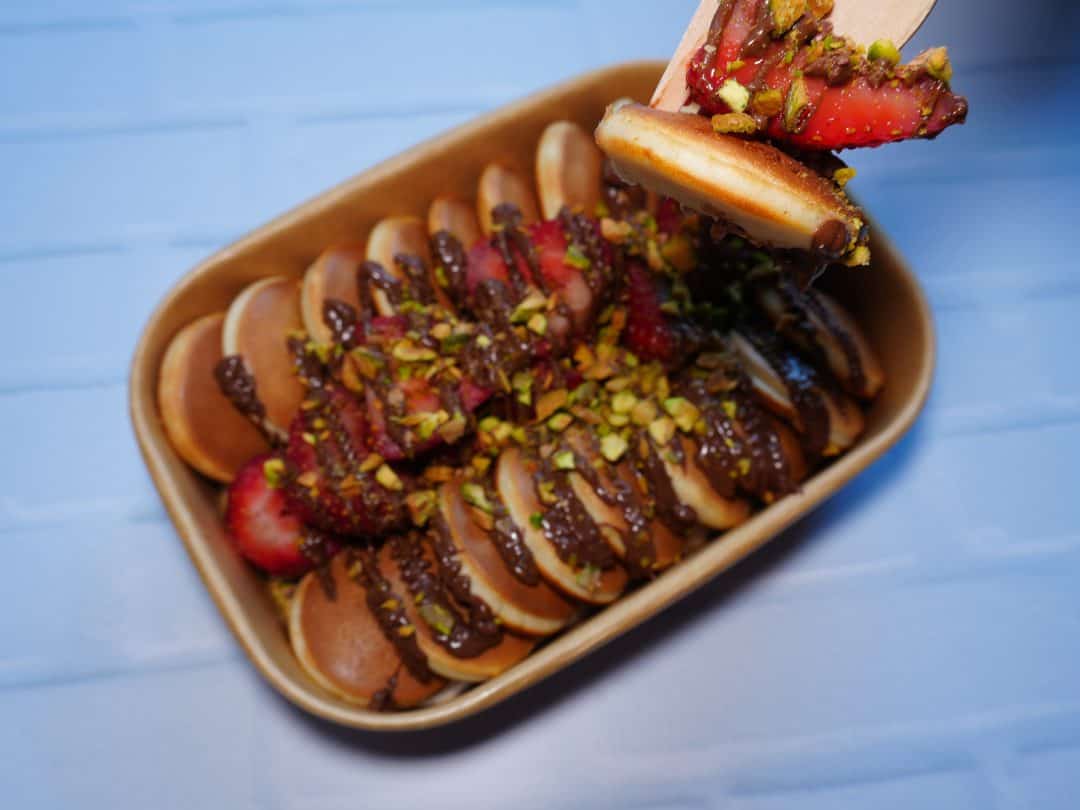 Dulces de chocolate y frutas en un recipiente de cerámica con cobertura de pistachos.