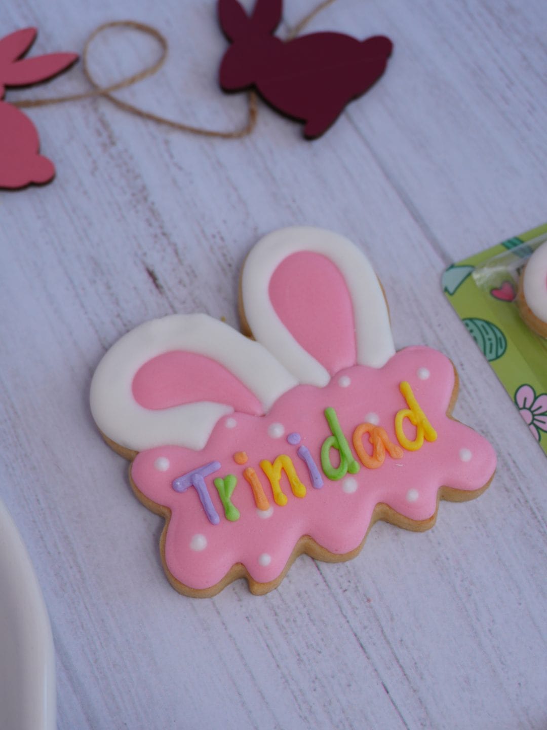 Galleta decorada en forma de conejito con nombre "Trinidad" para Pascua, decorada con glaseado rosa.
