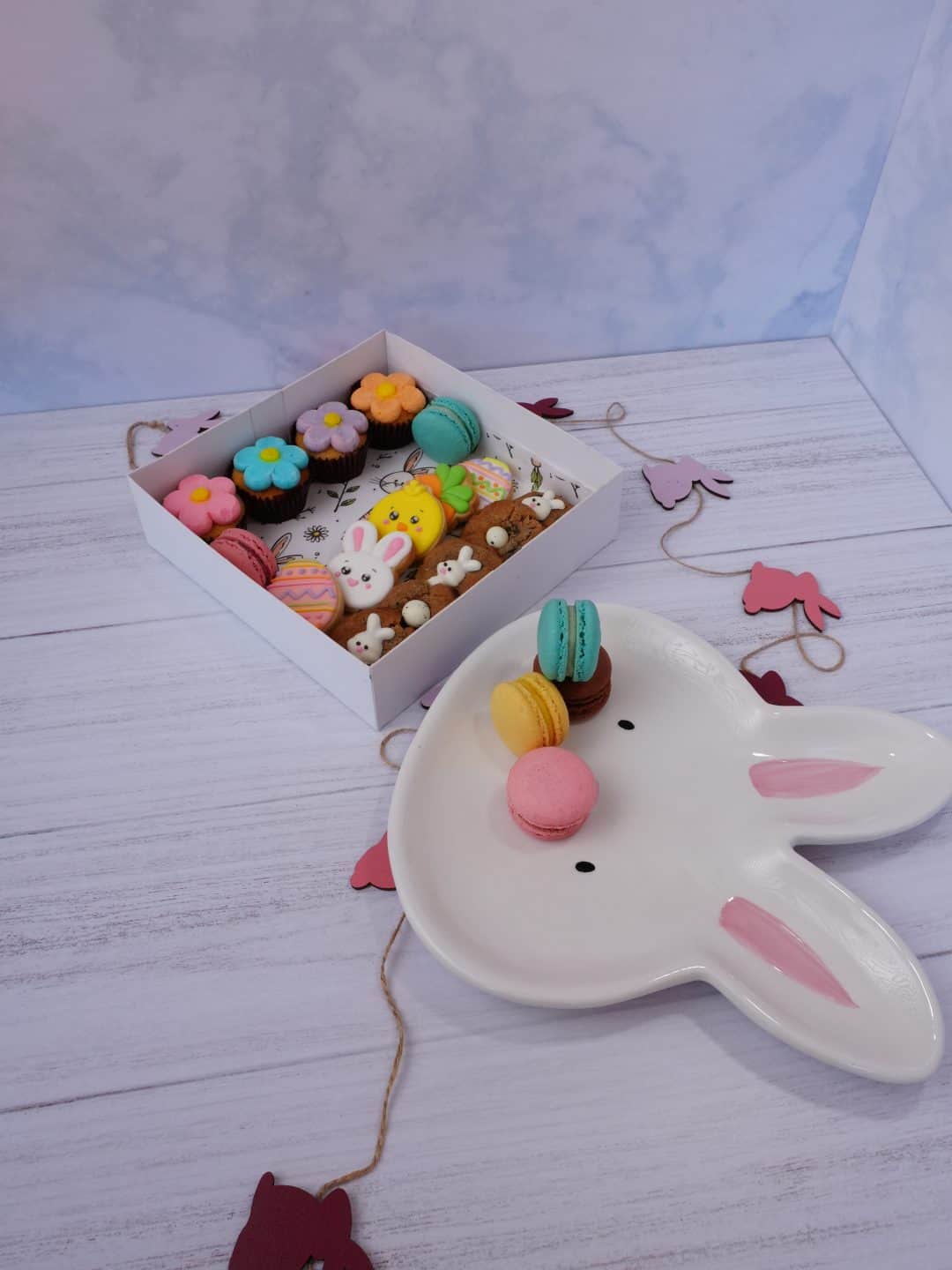 Galletas decoradas de Pascua en caja con conejitos y huevos de colores.