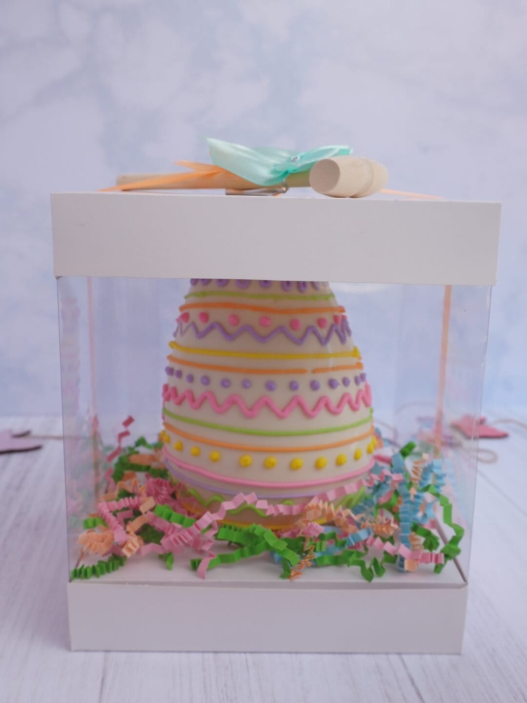 Galleta decorada de Pascua en caja transparente con la tapa levantada.